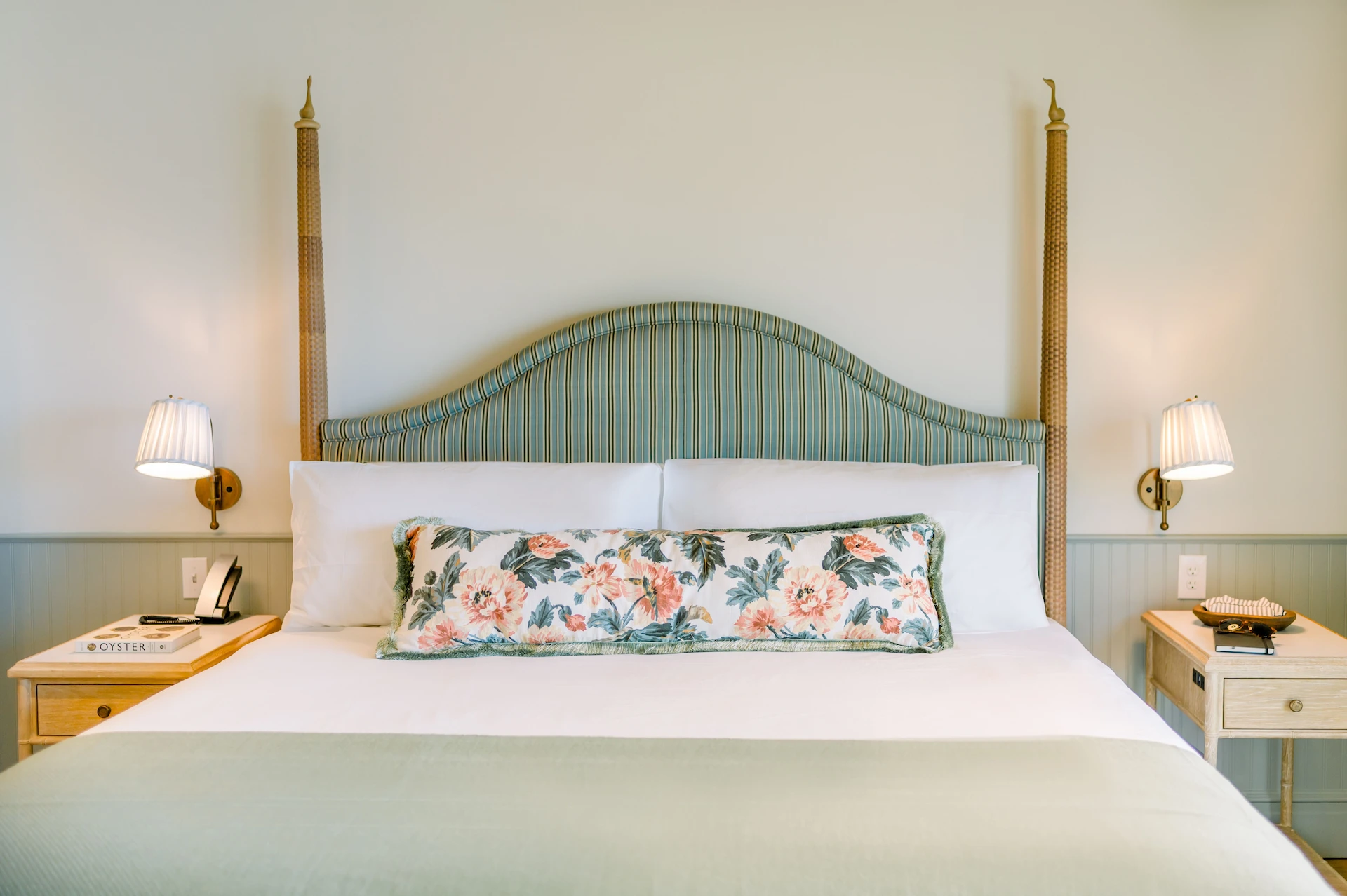 King-size bed with a vibrant floral pillow and two bedside lamps in a warmly decorated room.