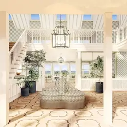 Lobby of The Sanderling Resort with a central sofa, plants, and a large central chandelier, filled with natural light.