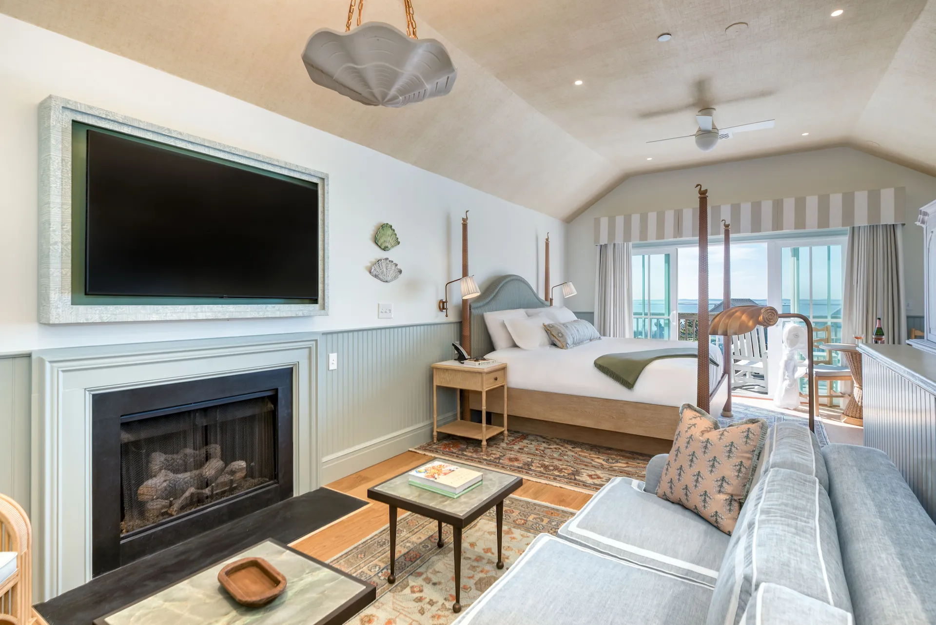 Cozy coastal-themed master bedroom with a sitting area, featuring a fireplace and television for a relaxing atmosphere.