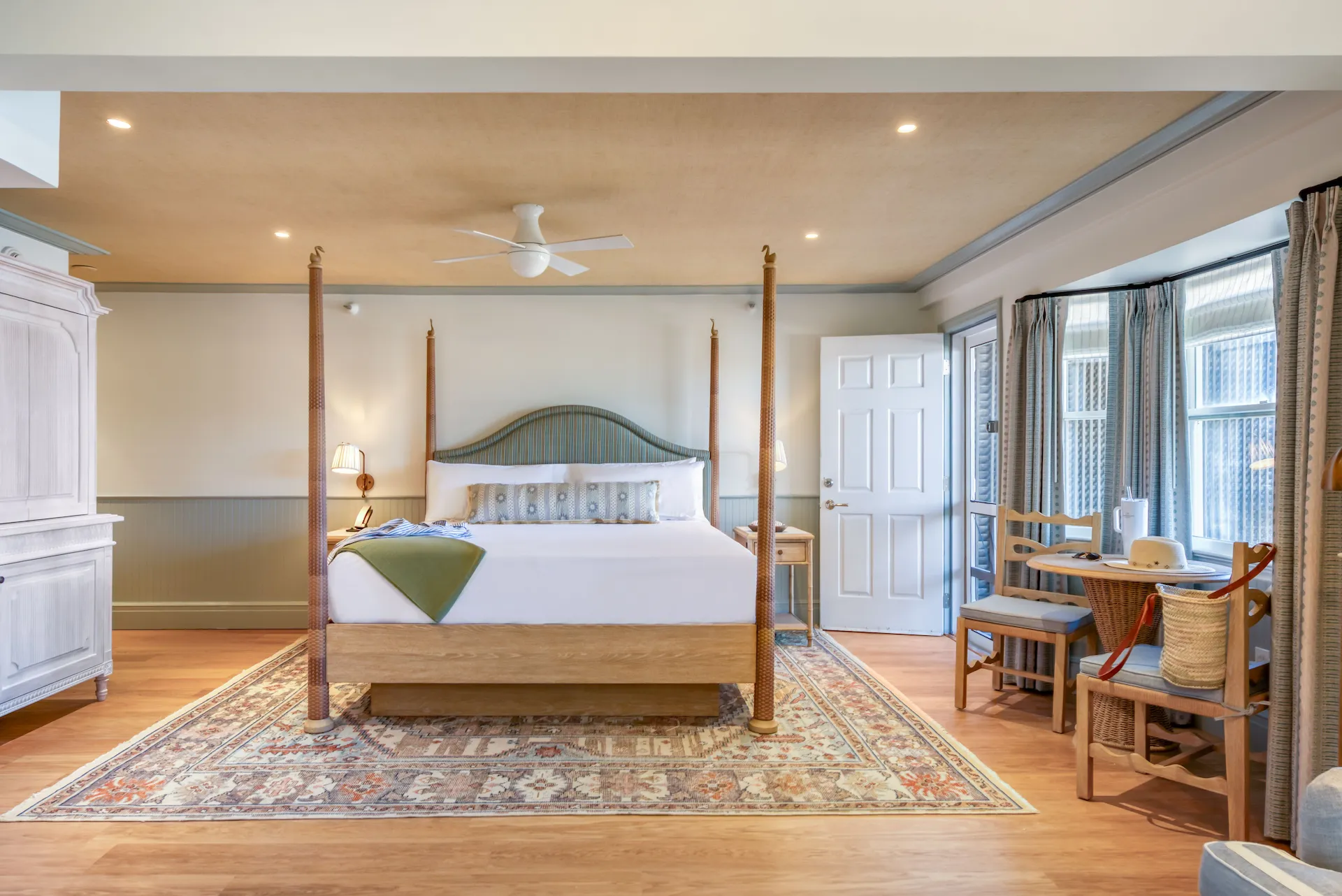 Spacious room in soothing green tones, combined with wooden accents, featuring a king-size bed and a cozy tea corner by the window.