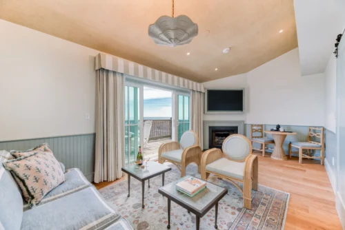 Spacious living room of the suite with a television, fireplace, and balcony offering sea views.