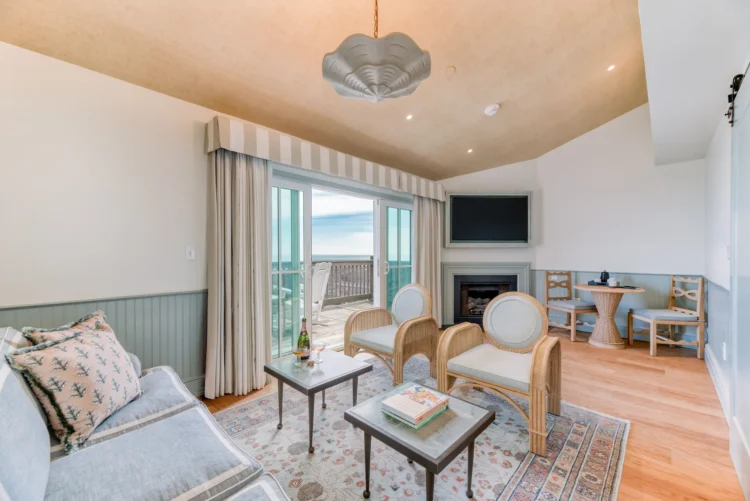 Spacious living room of the suite with a television, fireplace, and balcony offering sea views.