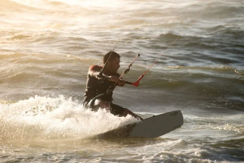 A man gliding over the waves, harnessing the wind as he enjoys an exhilarating kiteboarding session on the beach.