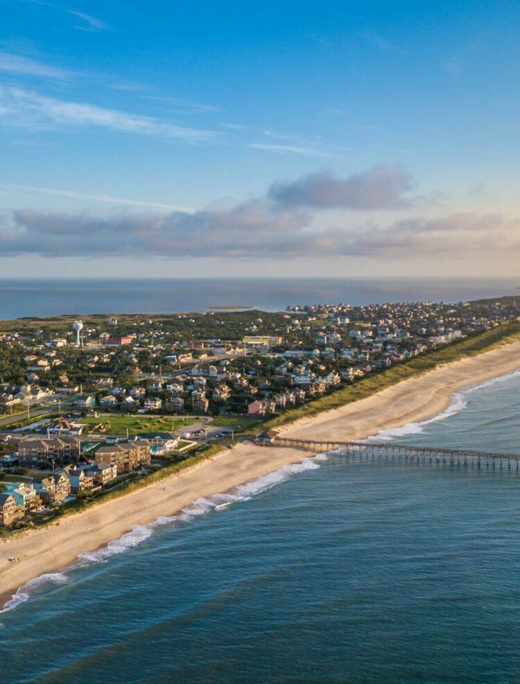 Aerial view of the coastline, highlighting the sea, sandy beaches, sky, and buildings, creating a beautiful and expansive landscape.