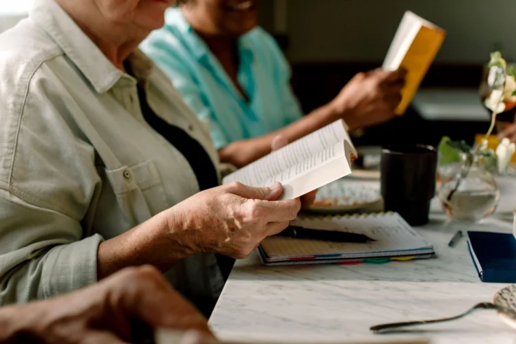 A group of people reading books and taking notes in a relaxed, cozy environment.