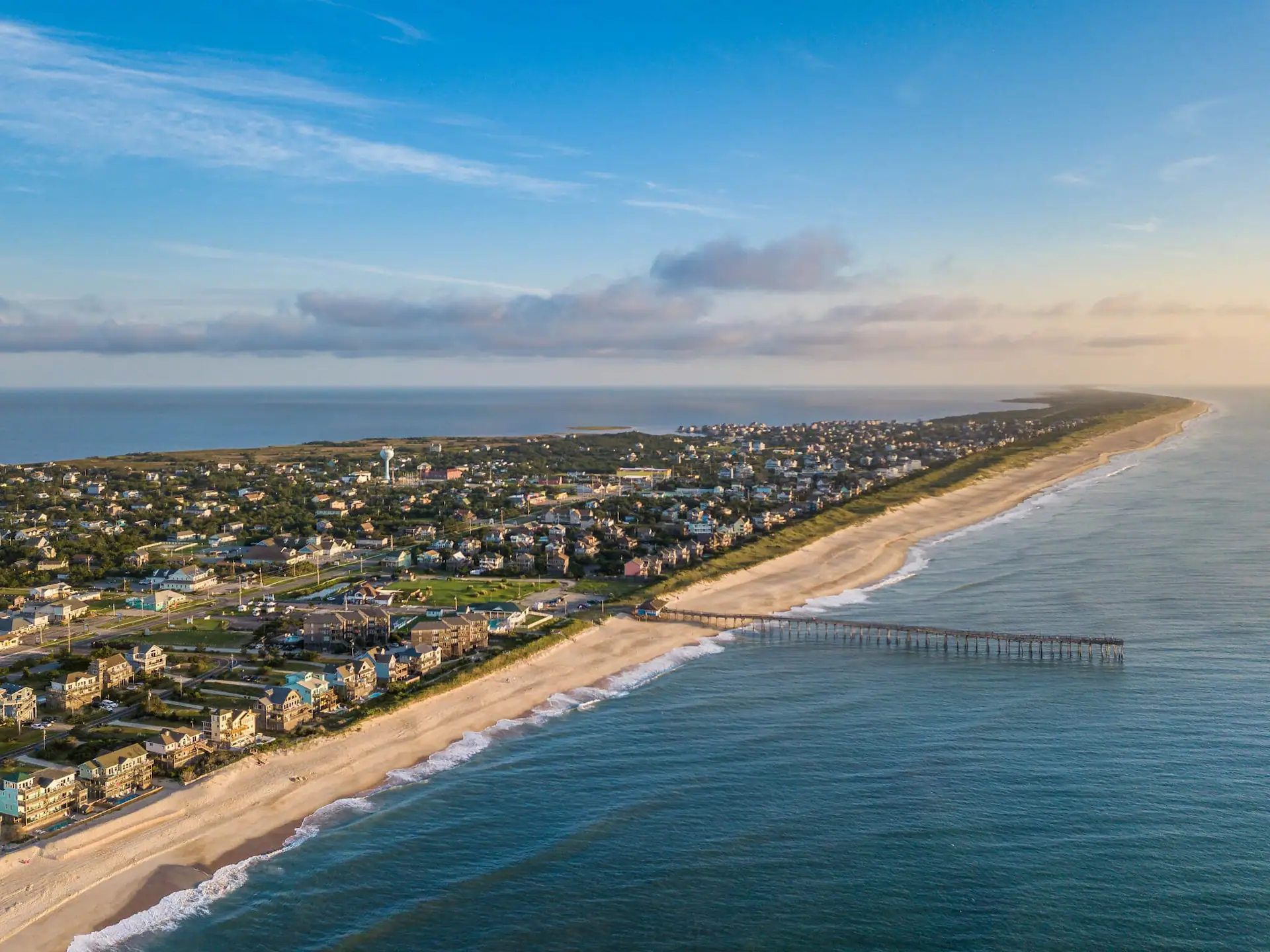 Aerial view of the coastline, highlighting the sea, sandy beaches, sky, and buildings, creating a beautiful and expansive landscape.