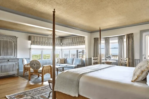 Spacious and bright room surrounded by windows with sea views, decorated in soft pastel blue tones and wood accents.
