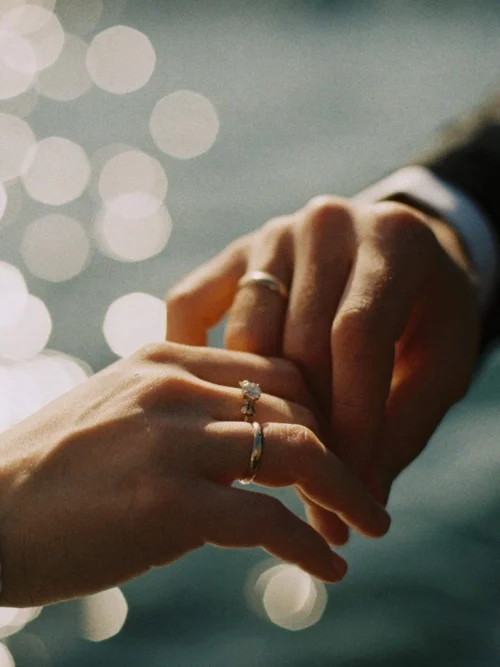 Newlyweds proudly showing their wedding rings, with their hands intertwined in a symbol of their union.